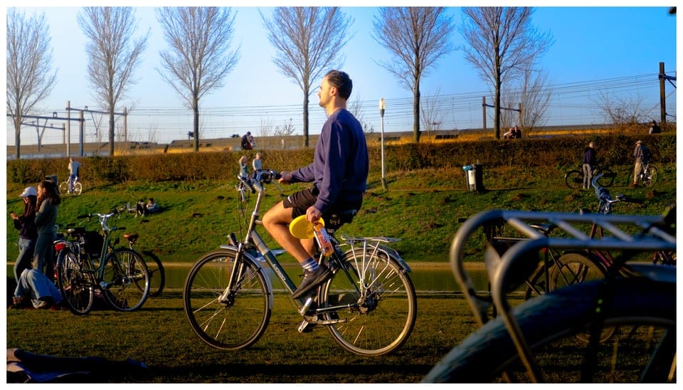 A person riding a bicycle with a bottle of wine.