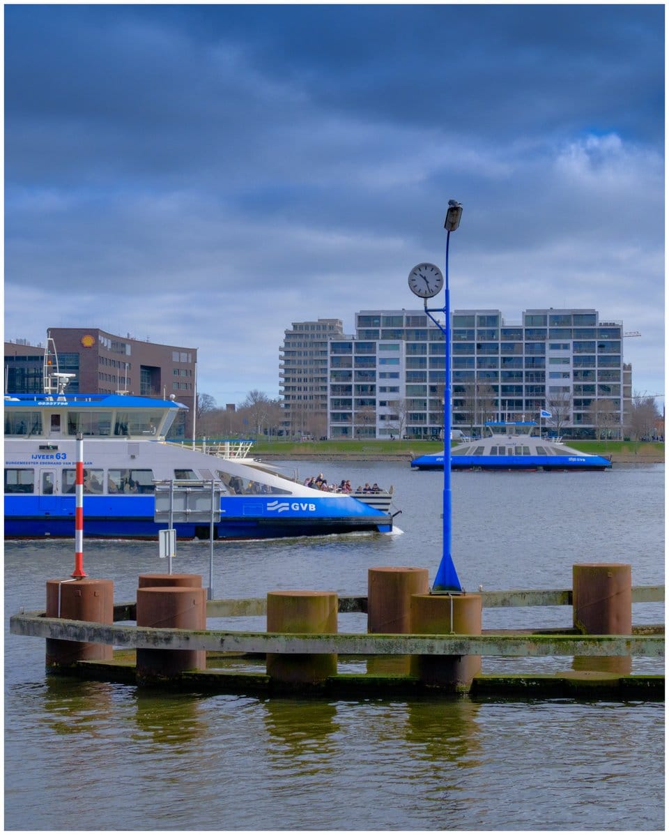 Two ferries crossing. In the first plane a dock with a clock