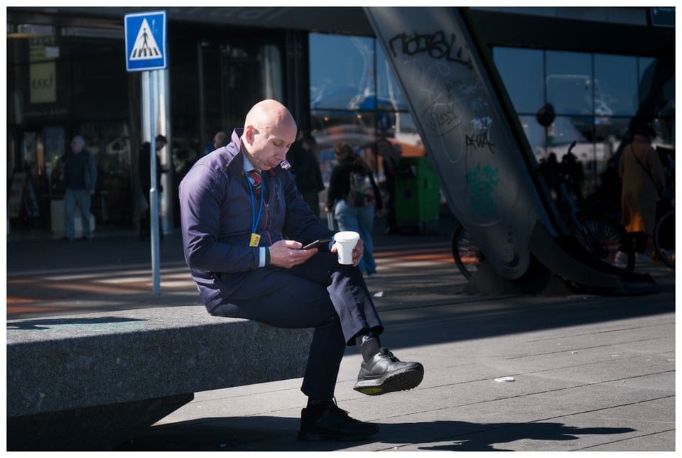 a man sitting on a bench looking at his phone