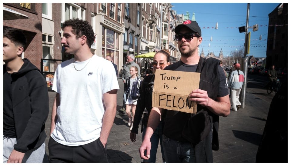 A person holding a sign that reads: Trump is a felon