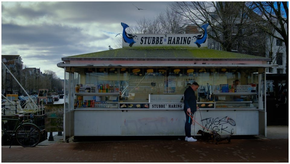 A man standing in front of a food stall.